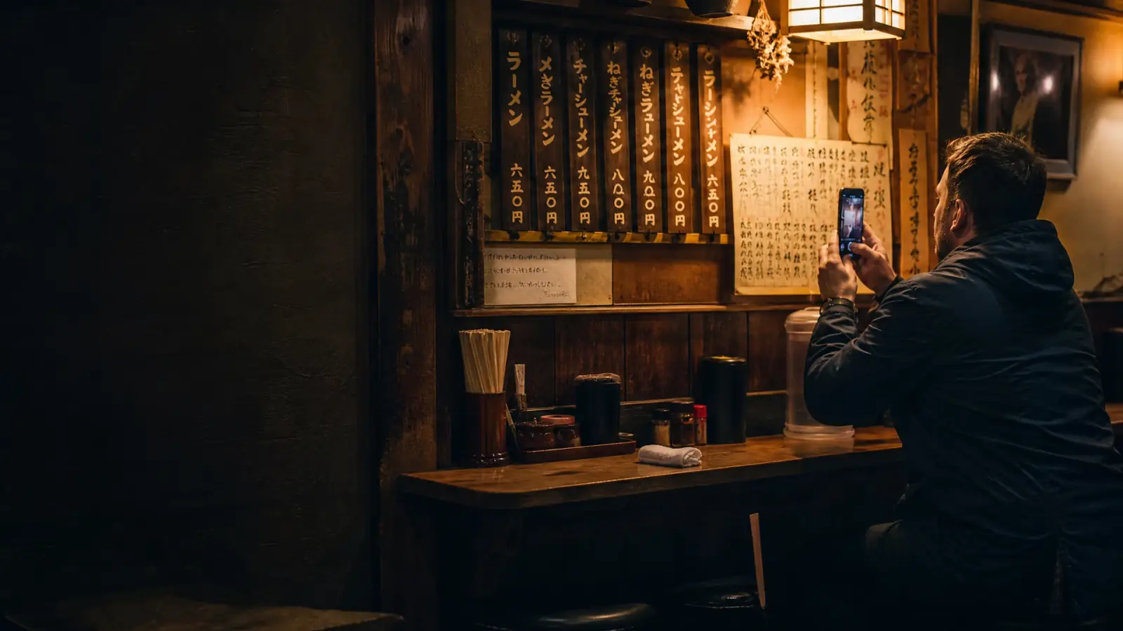 Western traveler photographing a menu in a small traditional Japanese restaurant